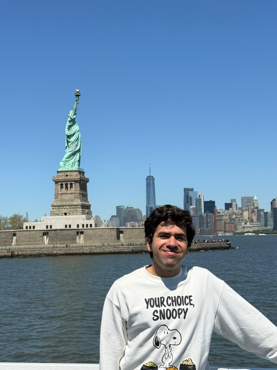 Dhruv with the Statue of Liberty and New York skyline behind him